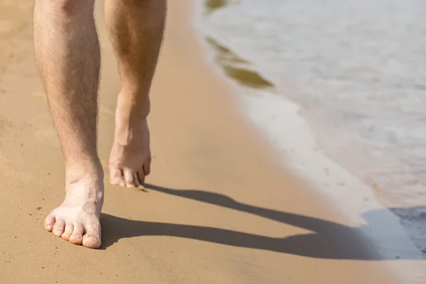 Man goes barefoot on the sand along the shore — Stock Photo, Image