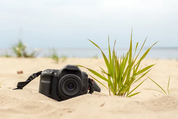 Moderna fotocamera reflex digitale sdraiata sulla sabbia sulla spiaggia — Foto Stock