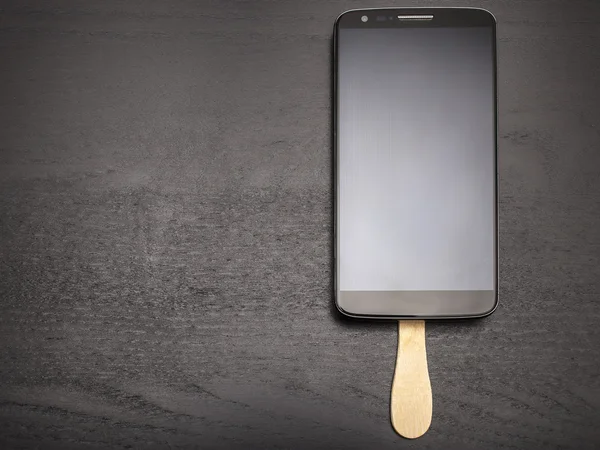 Karanlık bir arka plan üzerinde çikolatalı dondurma gibi bir sopa üstünde hareket eden telefon — Stok fotoğraf