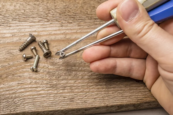 Hands holding screws using screwdrivers as food chopsticks — Stock Photo, Image
