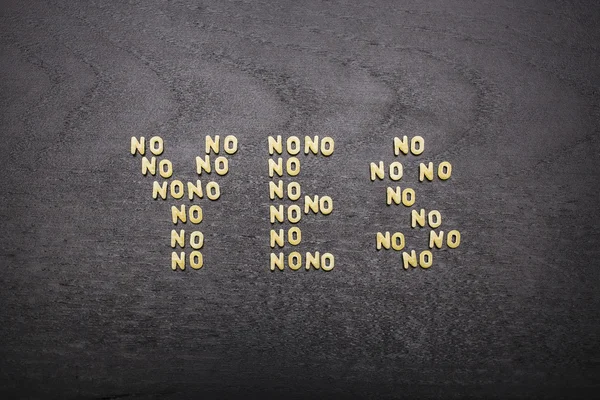 Die Antwort "Ja", die aus einer Reihe von Wörtern "Nein" besteht, mit kleinen Nudelbuchstaben auf einem dunklen Hintergrund eines Holzbretts, die die verborgene Bedeutung und Mehrdeutigkeit des Abkommens zeigen. (5172)) — Stockfoto