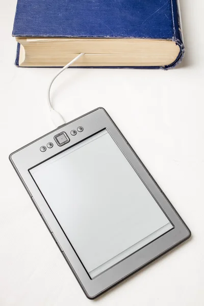 Электронная книга подключена к старой толстой синей книге кабелем — стоковое фото