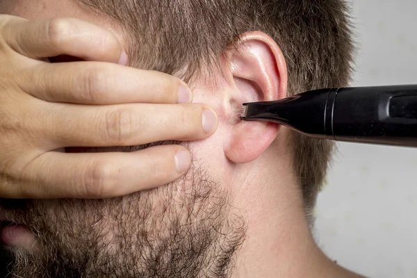 Homem barbudo corta o cabelo nos ouvidos — Fotografia de Stock