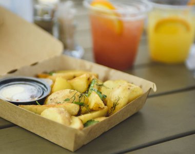 Karton bir kutuda kızarmış patates. Yaz sokak yemekleri. Salgın döneminde bir yaz restoranında öğle yemeği..