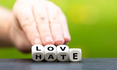 Hand turns dice and changes the word hate to love. clipart