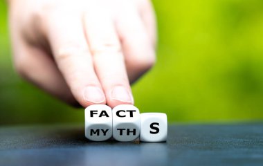 Hand turns dice and changes the word myths to facts. clipart