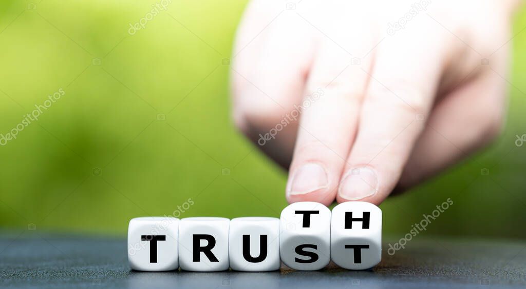 Hand turns dice and changes the word Trust to Truth.