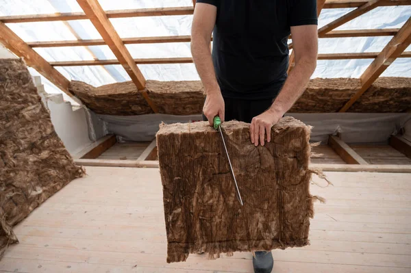 Craftsman cutting insulation material to insulate the attic.