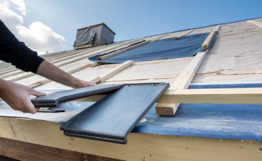 Roofer yeni bir çatıya düz fayanslar koyuyor.