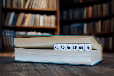 Bir kütüphanede açık bir kitap, içinde eğitim, bilgi ve kişisel gelişimi sembolize eden 