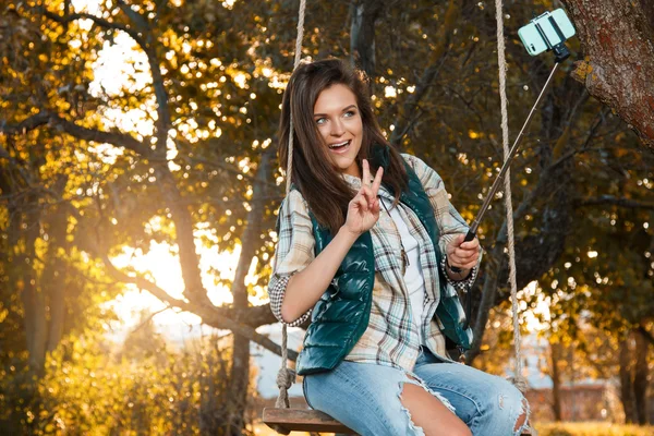Девушка делает селфи в осеннем парке — стоковое фото