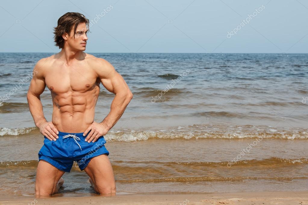 Muscular model posing on beach Stock Photo by ©AY_PHOTO 106353972