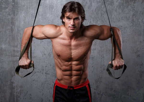 Muscular man with  suspension straps — Stock Photo, Image