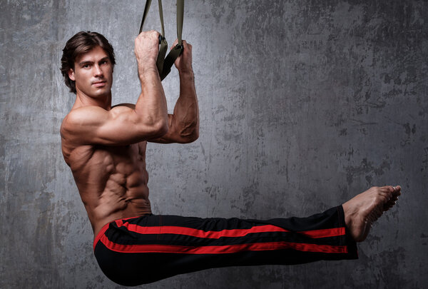 Muscular man with  suspension straps
