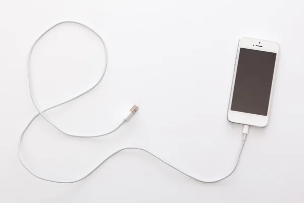 Смартфон и кабель на белом — стоковое фото