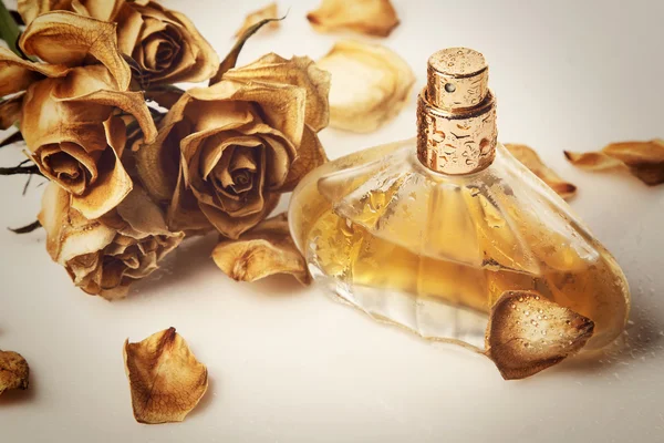 Fiolka z perfum i suchy kwiat róży — Zdjęcie stockowe