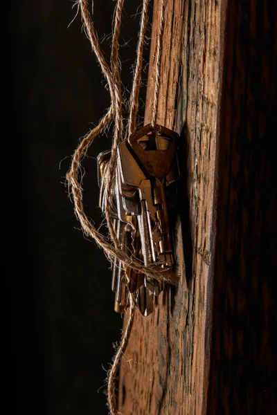 Verschiedene Tasten auf Gewinde über Holzoberfläche — Stockbild Verschiedene Schlüssel am Gewinde — Stockfoto