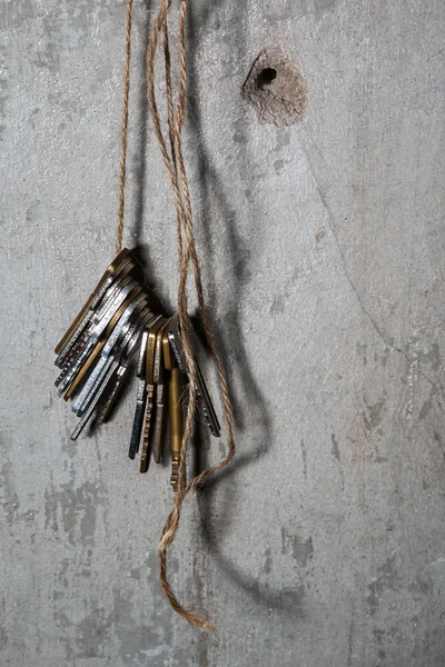 Schlüssel am Gewinde über Betonwand — Stockbild Verschiedene Schlüssel am Gewinde — Stockfoto