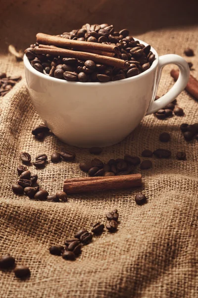 Taza, granos de café y palitos de canela — Foto de Stock