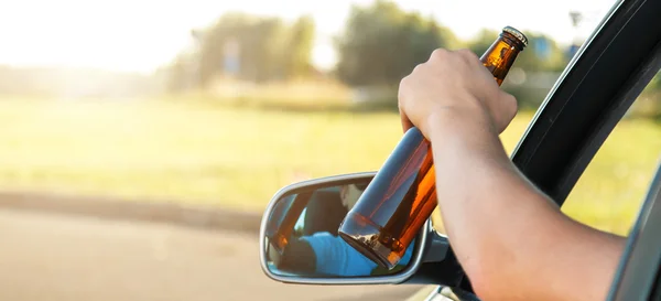 Car driver holding a bottle of beer — Stock Photo, Image