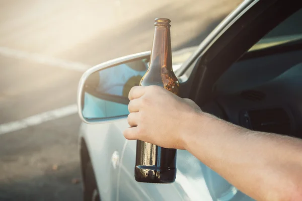 Car driver holding a bottle of beer — Stock Photo, Image