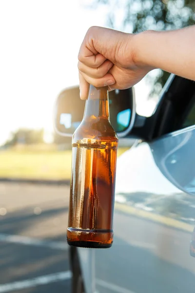 Car driver holding a bottle of beer — Stock Photo, Image