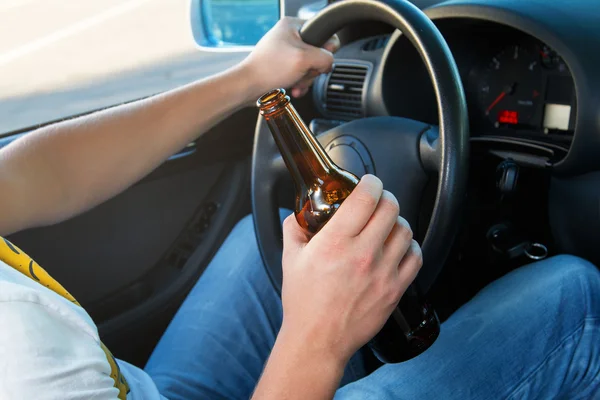 Car driver holding a bottle of beer — Stock Photo, Image