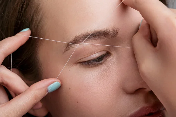 Eyebrow correction with a white thread — Stock Photo, Image