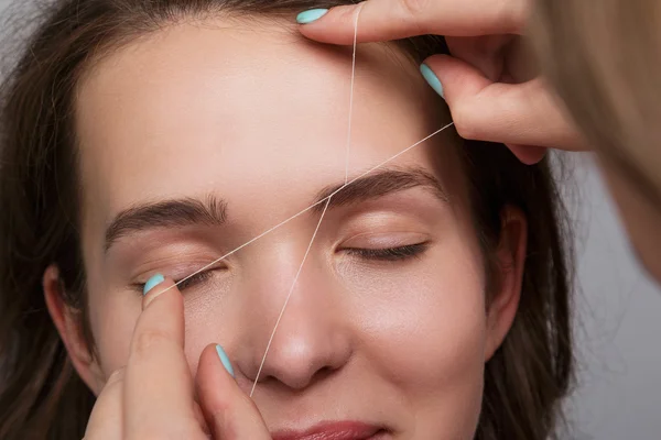 Eyebrow correction with a white thread — Stock Photo, Image