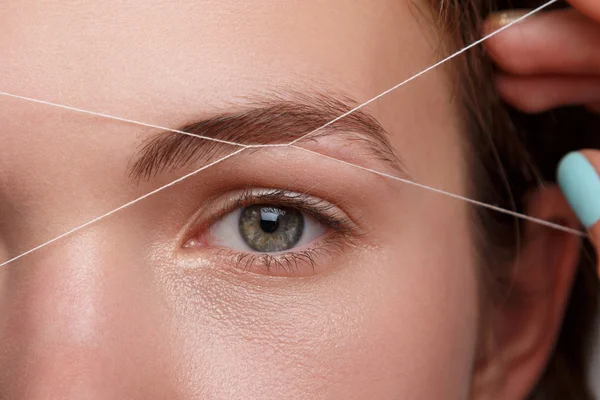 Eyebrow correction with a white thread Royalty Free Stock Images