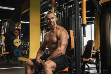 Spor yaparken spor salonunda çalışan yakışıklı ve kaslı vücutçunun portresi.