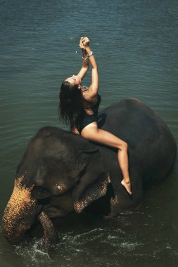 Mutlu genç kadın nehirde fille banyo yapıyor.