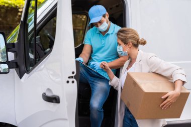 Önleme maskeleri yeni güvenlik önlemleri. Karavandaki teslimatçıdan paket alan genç bir kadın.