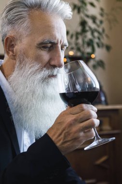 Şık ve yakışıklı sakallı adam kırmızı şarap içiyor.