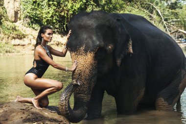 Mutlu genç kadın nehirde fille banyo yapıyor.