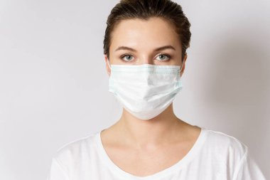Genç beyaz kadın virüse karşı korunmak için maske takıyor.