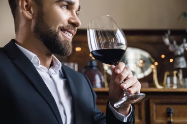 Bir bardak kırmızı şarapla yakışıklı sakallı adamın portresi.