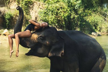 Mutlu genç kadın nehirde fille banyo yapıyor.