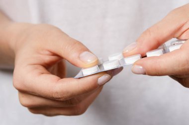 Kadın elinin folyo ambalajlı bir hapla kapatılması.