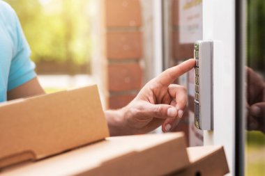 Paket taşıyan teslimatçı elleri, kapı zilinin tuşlarına basıyor.