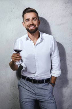 Yakışıklı sakallı şarap garsonu kırmızı şarabı tadıyor.