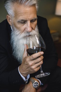 Şık ve yakışıklı sakallı adam kırmızı şarap içiyor.