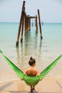 Genç kadın hamakta dinleniyor kırık iskeleden sarkan eski kirişlere asılı.