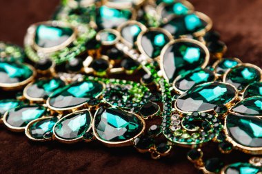 Kahverengi kadife arka planda yeşil değerli taşlar olan lüks bir kolye.