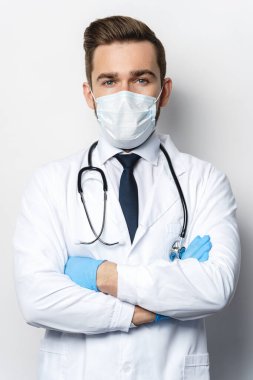 Steteskoplu kendine güvenen doktor koruyucu maske ve lateks eldiven takıyor.