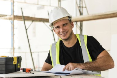 Young, inşaat sahasının planları üzerinde çalışıyor.