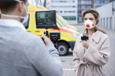 Önleme maskesi takan kameraman ve gazeteci. TV muhabirleri şehirdeki bir virüs salgını hakkında haber yapıyorlar..