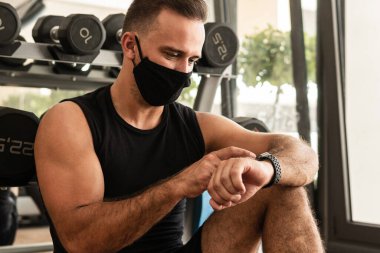 Yeni normal konsept. Spor salonundaki antrenmanı sırasında koruyucu yüz maskesi takan genç bir atletik..