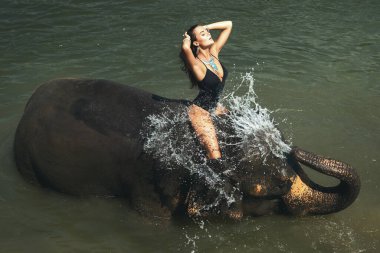 Mutlu genç kadın nehirde fille banyo yapıyor.