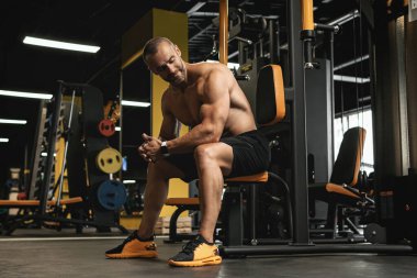 Spor yaparken spor salonunda çalışan yakışıklı ve kaslı vücutçunun portresi.